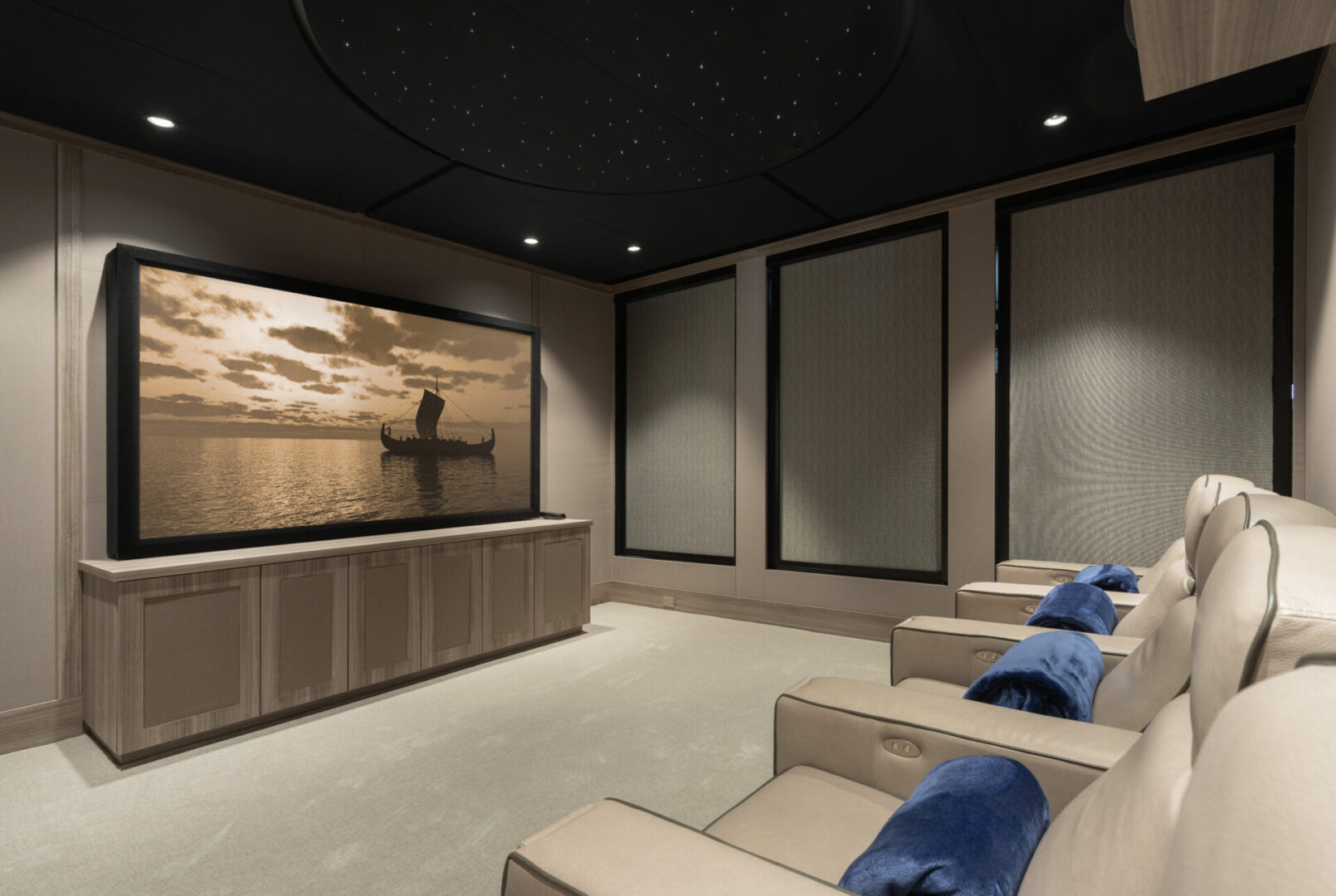 A media room with a big TV and cream-colored reclining chairs